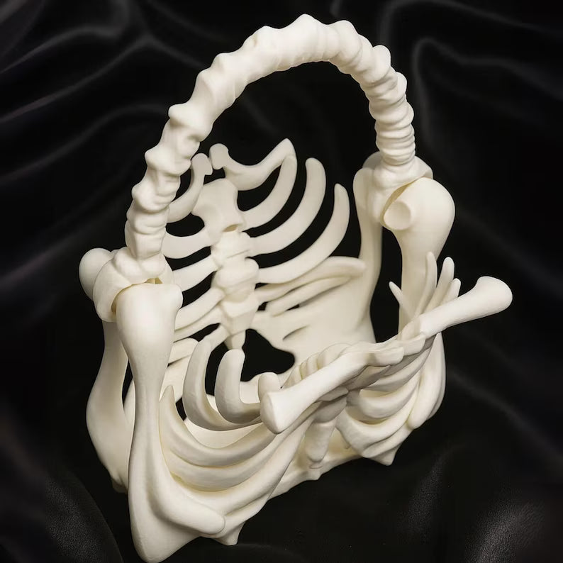 White ceramic basket shaped like a skeleton on a black background