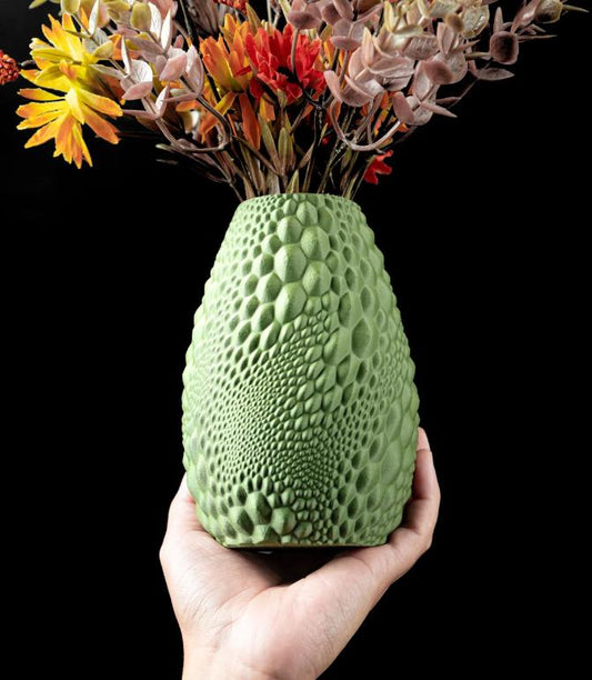 Hand holding eco-friendly 3D printed Gato flower vase in custom green color with textured organic pattern and dried flowers.
